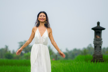 outdoors holidays portrait of middle aged attractive and elegant Asian woman in white dress enjoying beauty of nature at tropical green field playful and carefree