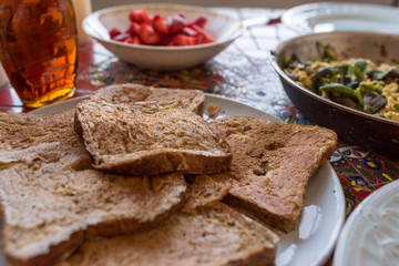 Head on view of a pile of diary free french toast dipped in almond milk with tofu scramble and strawberries at the back