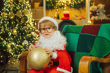 Fototapeta na wymiar Little Santa. A child holds a Christmas tree toy.