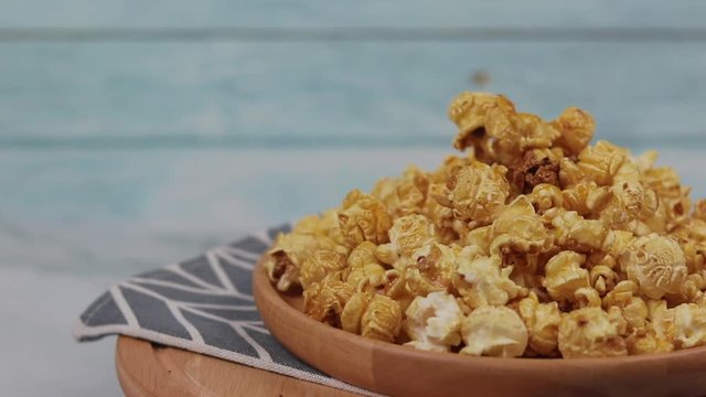 Caramel popcorn in a wooden plate  roating , Golden caramel popcorn closeup ,  Background of popcorn. Snacks and food for a movie 