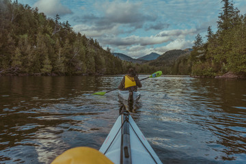 Woman in a white kayak deep in the Adirondacks wilderness