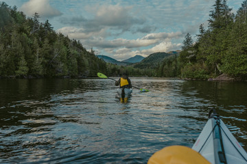 Young woman kayaks deep into the Adirondack wilderness on a lake