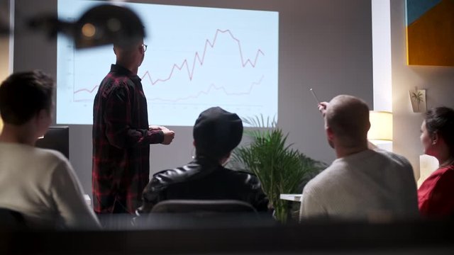 Business meeting. Office Team Analyzes Business Growth. Young Man Interested In Audience. On Screen Growth Graph Monitor