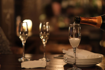 Pouring champagne into glasses on table at night. blur background