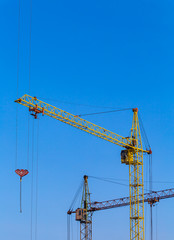 Two cranes with a light blue sky background. Construction site. Old construction equipment. 
