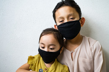 Asian young kids are wearing hygienic reusable face mask to prevent the virus. Siblings family sickness prevention.