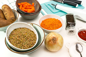 Lentil soup ingredients.  Red lentils, green lentils, onion, carrot, potatoes, and some seasoning close up on white background