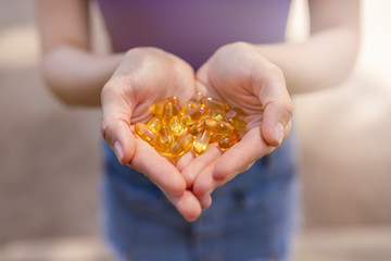 Fototapeta premium A handful of vitamin d capsules are in women's hands. Blurred background
