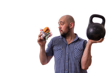 A bearded, fat man with a Burger and a weight in his hands. The concept of a healthy lifestyle