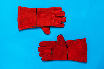 A pair of bright welding gloves on a blue background.