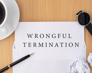 Wrongful termination document on wooden table with pen and smartwatch, termination of employment and resignation concept