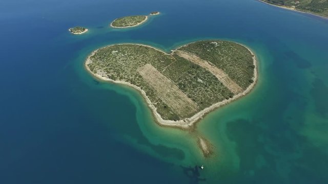Aerial tilt down shot of small islands in sea on sunny day, drone flying backward over ocean - Biograd, Croatia