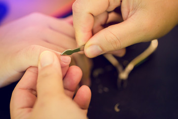 Selective focus to mother hands using white nail file for son. Mother doing manicure with nail file and cutting nails her kid. 