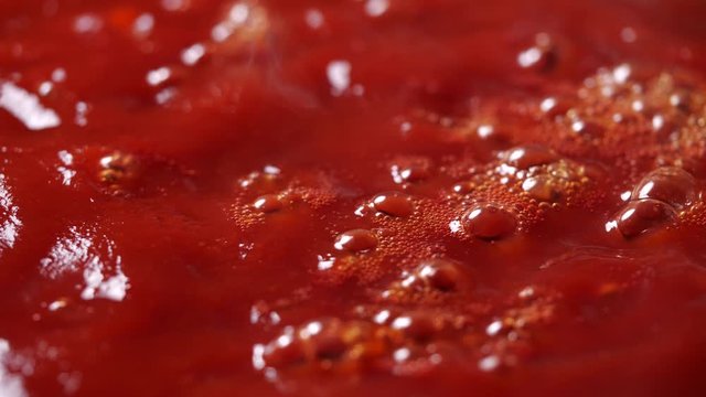 Close-up of boiling red tomato sauce in a pan with steam in 4K Resolution