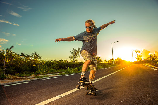Skater rides on a highway against the backdrop of incredible sunset