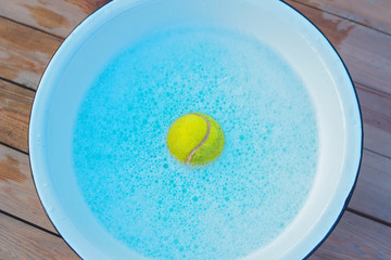 washing tennis ball with soap and water to disinfect it