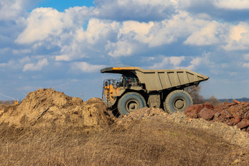 Obraz premium Huge yellow mining dump truck working in iron ore quarry. Mining industry