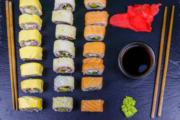 Set of sushi rolls on a black stone slate. Top view
