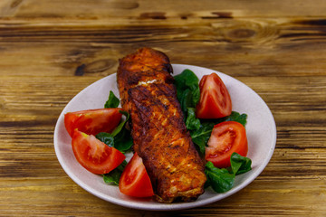 Grilled salmon fillet with spinach and tomatoes on wooden table