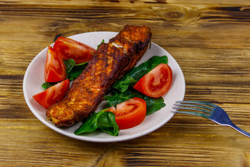 Grilled salmon fillet with spinach and tomatoes on wooden table