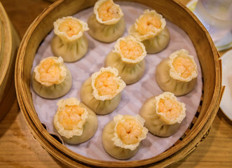 Traditional steamed Chinese har gow dumplings with shrimp and pork in a steamer basket at a restaurant in Singapore