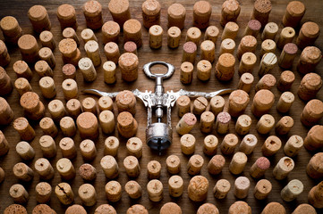 Wine corks of different sizes and a corkscrew standing upright on an old wooden surface. Background for liquor.