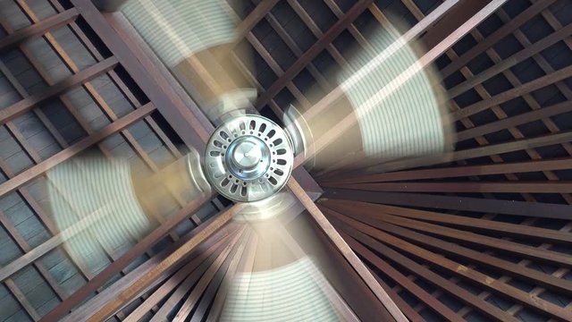 Ceiling fan spins under wooden villa ceiling at tropical resort, ceiling fan is a mechanical fan mounted on the ceiling of a room or space,