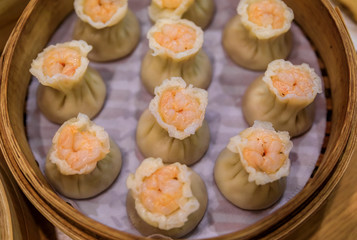 Traditional steamed Chinese har gow dumplings with shrimp and pork in a steamer basket at a restaurant in Singapore