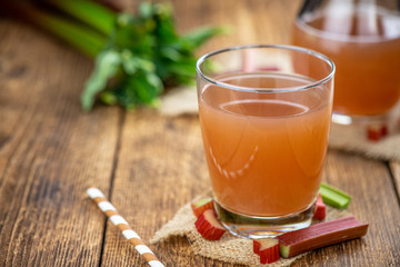 Old wooden table with fresh made Rhubarb Juice (close up; selective focus)