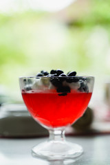 in the foreground there is a red jelly cream on top of white cream and honeysuckle