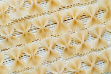 in the foreground, a pattern of raw macaroni in the form of bows, in the background, white long raw noodles