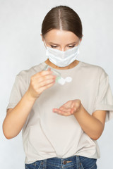 Beautiful caucasian girl in a doctor’s coronavirus medical mask uses antiseptics to cleanse her hands. Prevention of virus infection.