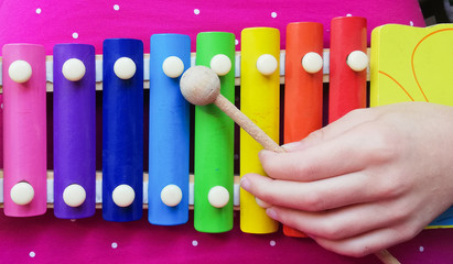 Child's hand playing colourful xylophone