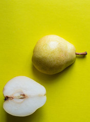 Yellow fresh pear cut in half on yellow background. Top view.