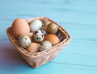 wicker basket with quail and compartment eggs on a gray background