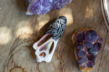 Beautiful shell pendant on wooden backround with amethyst druses