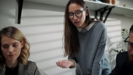 In Creative Office Productive Coworkers Standing at the Table, Company Meeting. Colleagues and clients talking strategy with laptop and tablet.