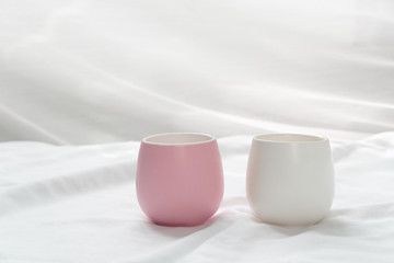 pink white ceramic cup for tea drink on soft fabric with morning light interior background