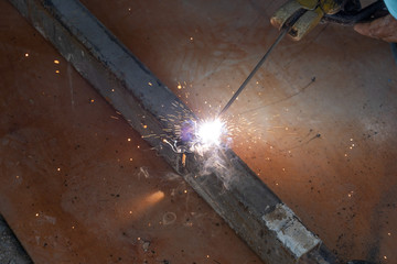 Industry worker welding iron pieces at work
