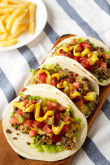 Homemade Cheeseburger Tacos and French Fries on cloth, low angle view.