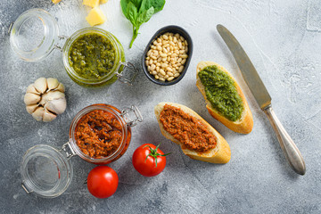 red and green pesto  and cooking italian recipe ingredients  Parmesan cheese, basil leaves, pine nuts,  tomatoes  breakfast panini with sauce top view on grey concrete surface  space for text