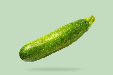 Flying in air fresh green zucchini isolated on pastel green background.