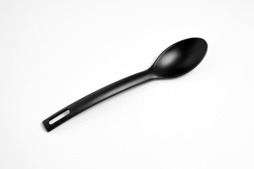 Black plastic big spoon.Plastic kitchen utensil. Isolated on white background. High-resolution photo.