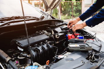Auto mechanic using measuring equipment for checking car battery. Concepts of car Repair service and car insurance.