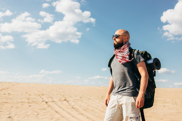 Tourism, destination and travel. Tourist with backpack traveling through desert. Man surviving in sands. Trekking, hiking, active lifestyle and touristic equipment