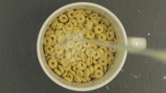 Overhead Top View of cereal rings with Milk falling in bowl in slow motion Resolution 4K Froot Loops Milk is being poured into bowl. Nourishing healthy Natural breakfast. 
