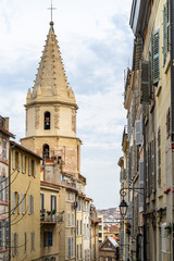 Fototapeta na wymiar A typical street at Le Panier quarter in Marseille with the bell tower of the church of Notre Dame des Accoules, France