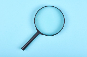 Black magnifying glass on blue background.
