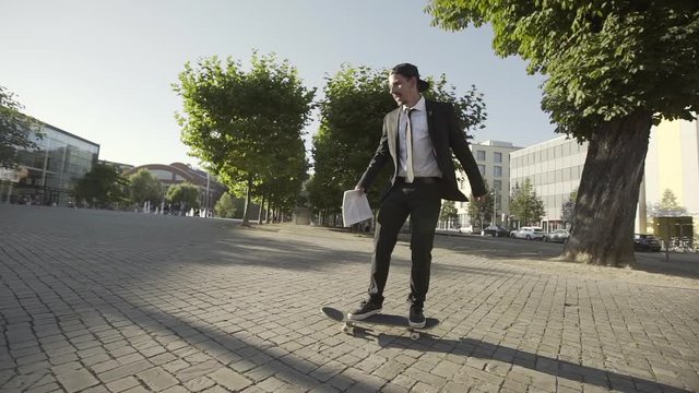 Full length of young man in suit skateboarding on footpath in city during sunny day - Erfurt, Germany