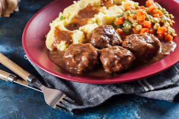 Roasted meatballs in dark sauce with mashed potatoes
